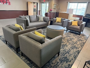 A modern living room with a sectional sofa, armchairs, and a round ottoman.