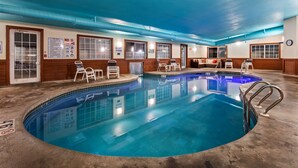 A large indoor pool with clear blue water, surrounded by lounge chairs and a seating area with a sofa and table. - Best Western Dodgeville Inn & Suites (Dodgeville)