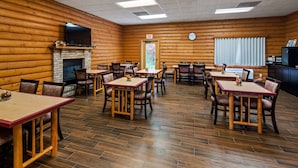 A log cabin-style restaurant with wooden walls, a fireplace, and multiple tables and chairs. - Best Western Dodgeville Inn & Suites (Dodgeville)