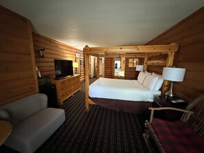 Ein rustikal eingerichtetes Zimmer im Chalet-Stil mit einem Bett, einem Fernseher, einer Couch und einem Sessel.