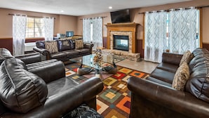 A living room with leather sofas, a glass coffee table, a fireplace, and patterned curtains. - Best Western Dodgeville Inn & Suites (Dodgeville)