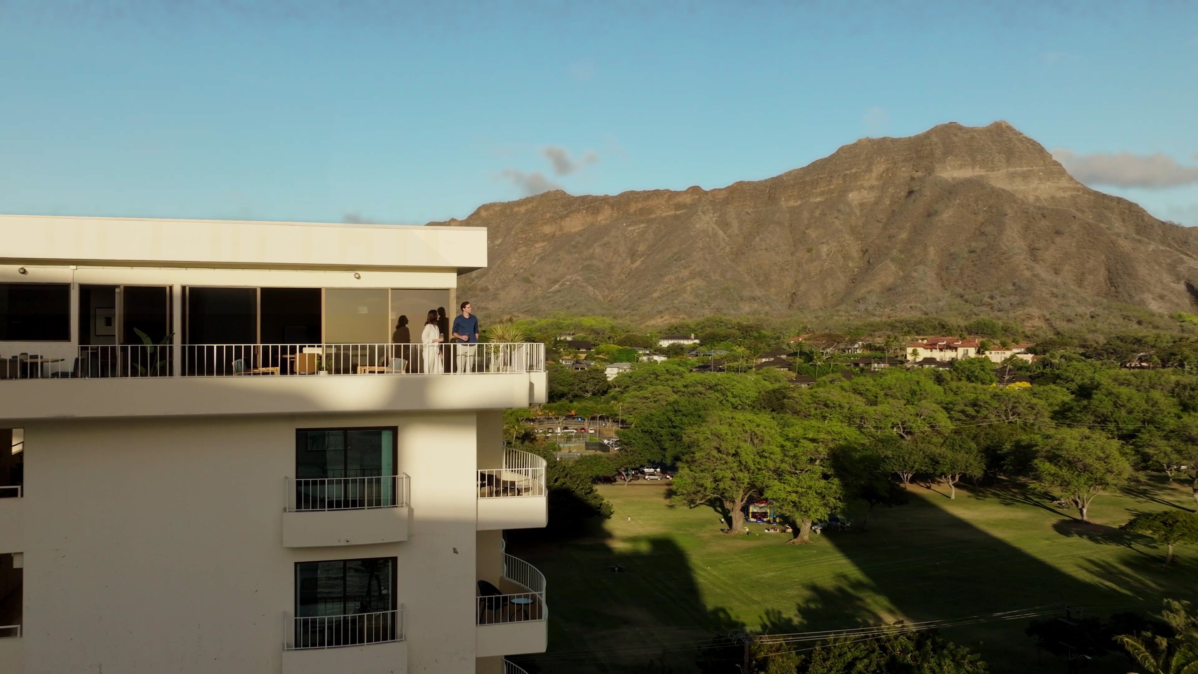 Un edificio de varios pisos con balcones que dan a un paisaje montañoso.
