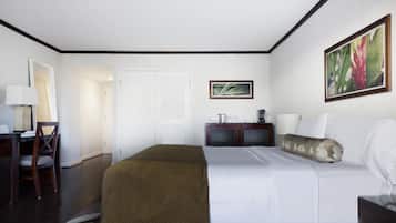 A hotel room with a bed, a desk with a chair, a wardrobe, and a painting on the wall.