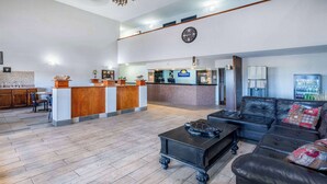 A spacious lobby with a reception desk, a black leather sofa, and a coffee table. - Days Inn by Wyndham Lamar (Lamar)