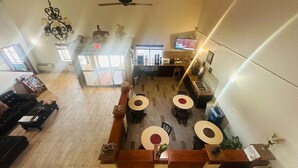 A spacious hotel lobby with a high ceiling, a central seating area with round tables, a ceiling fan, and a television mounted on the wall. - Days Inn by Wyndham Lamar (Lamar)