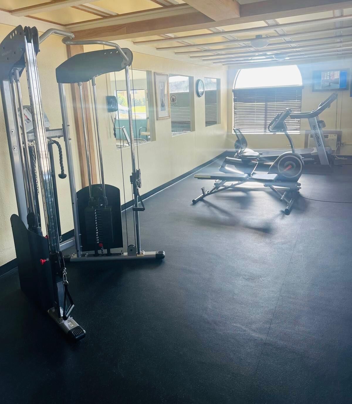 Un gimnasio con equipamiento de ejercicio, cinta de correr y bicicleta estática.