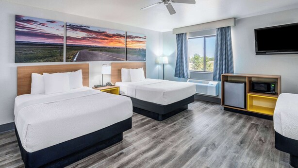 A hotel room with two beds, a desk, a TV, and a window with curtains. - Days Inn by Wyndham Lamar (Lamar)