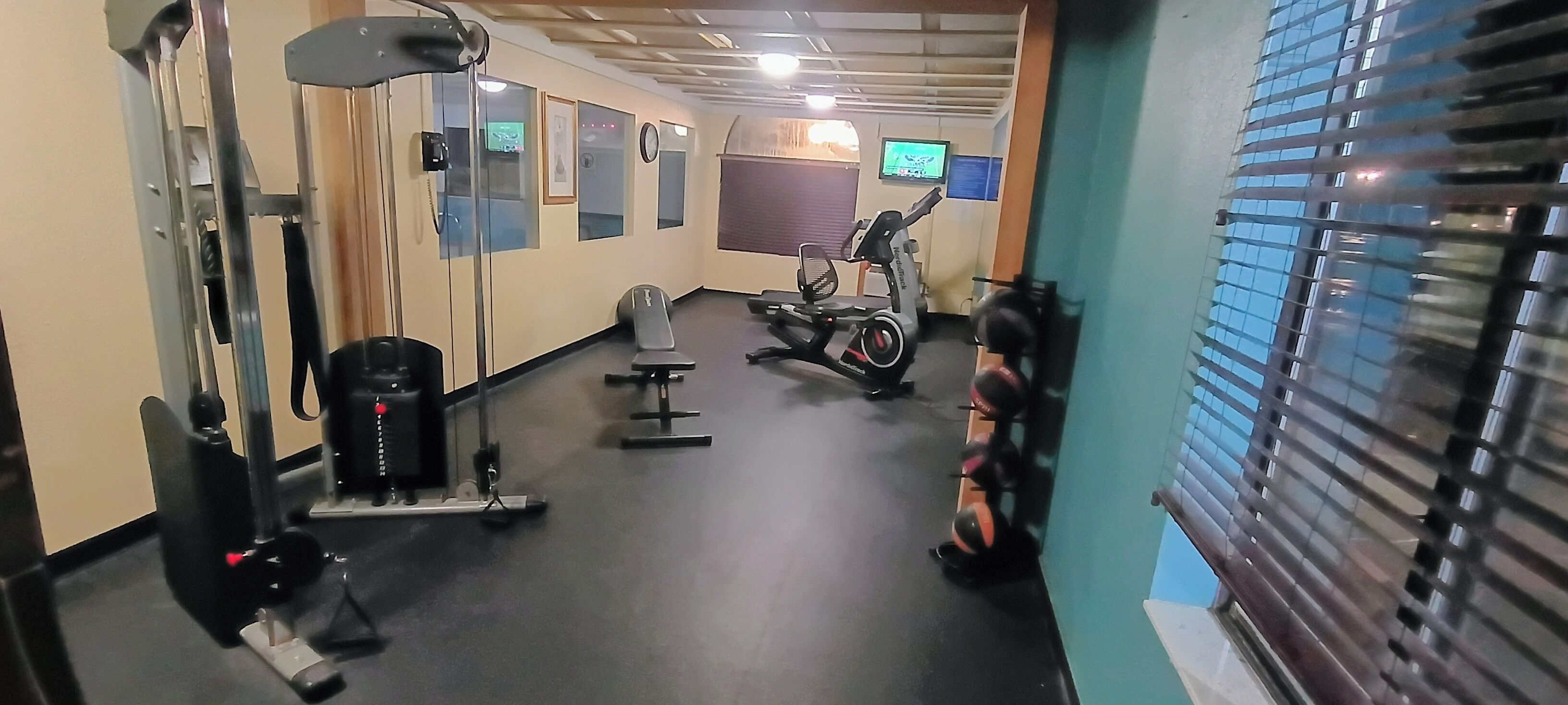 A gym with exercise equipment, a treadmill, and a wall-mounted TV.