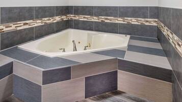 Un baño moderno con una bañera independiente, paredes con azulejos y piso de madera.