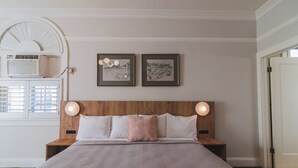 A bedroom with a wooden headboard, two bedside tables, a bed with a pink blanket, and two framed pictures on the wall. - Historic Sonora Inn (Sonora)