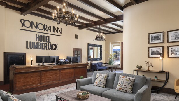 A hotel lobby with a reception desk, sofas, a chandelier, and framed pictures on the wall. - Historic Sonora Inn (Sonora)