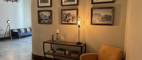 Una sala de estar con un sofá, una mesa con velas, una lámpara de pie y cuadros en la pared.