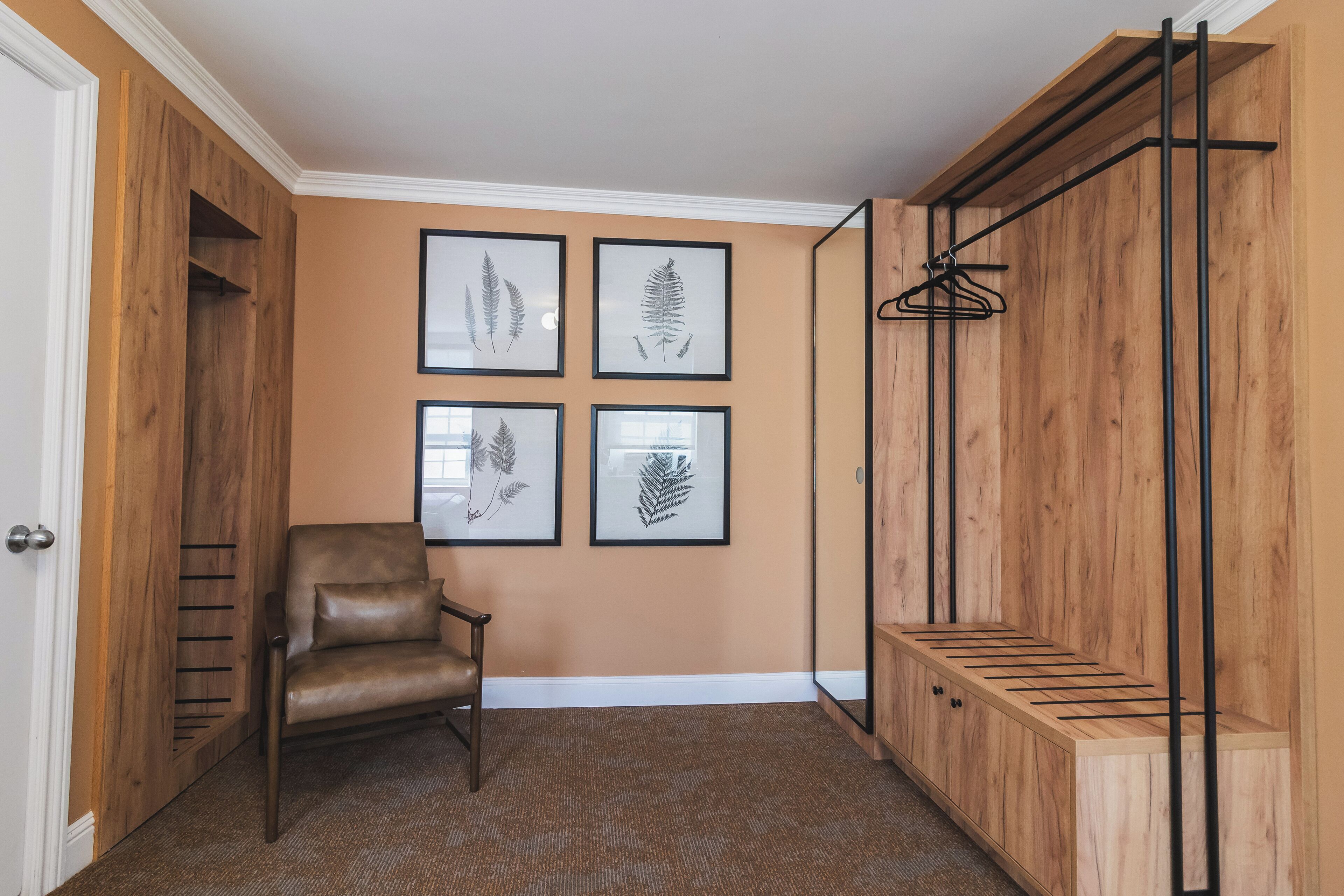 Um quarto com uma poltrona de couro marrom, estantes de madeira e gravuras botânicas emolduradas na parede.