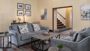 A living room with a grey sofa, a wooden coffee table, and a staircase leading to an upper floor. - Historic Sonora Inn (Sonora)