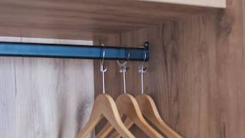 Un armario de madera con una barra metálica y perchas de madera.