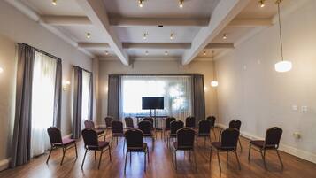 Una sala de conferencias con pisos de madera, un televisor de pantalla plana grande y filas de sillas moradas.