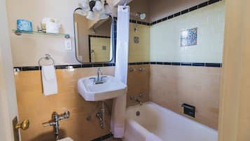 A bathroom with a bathtub, a sink, a mirror, and a shower curtain.