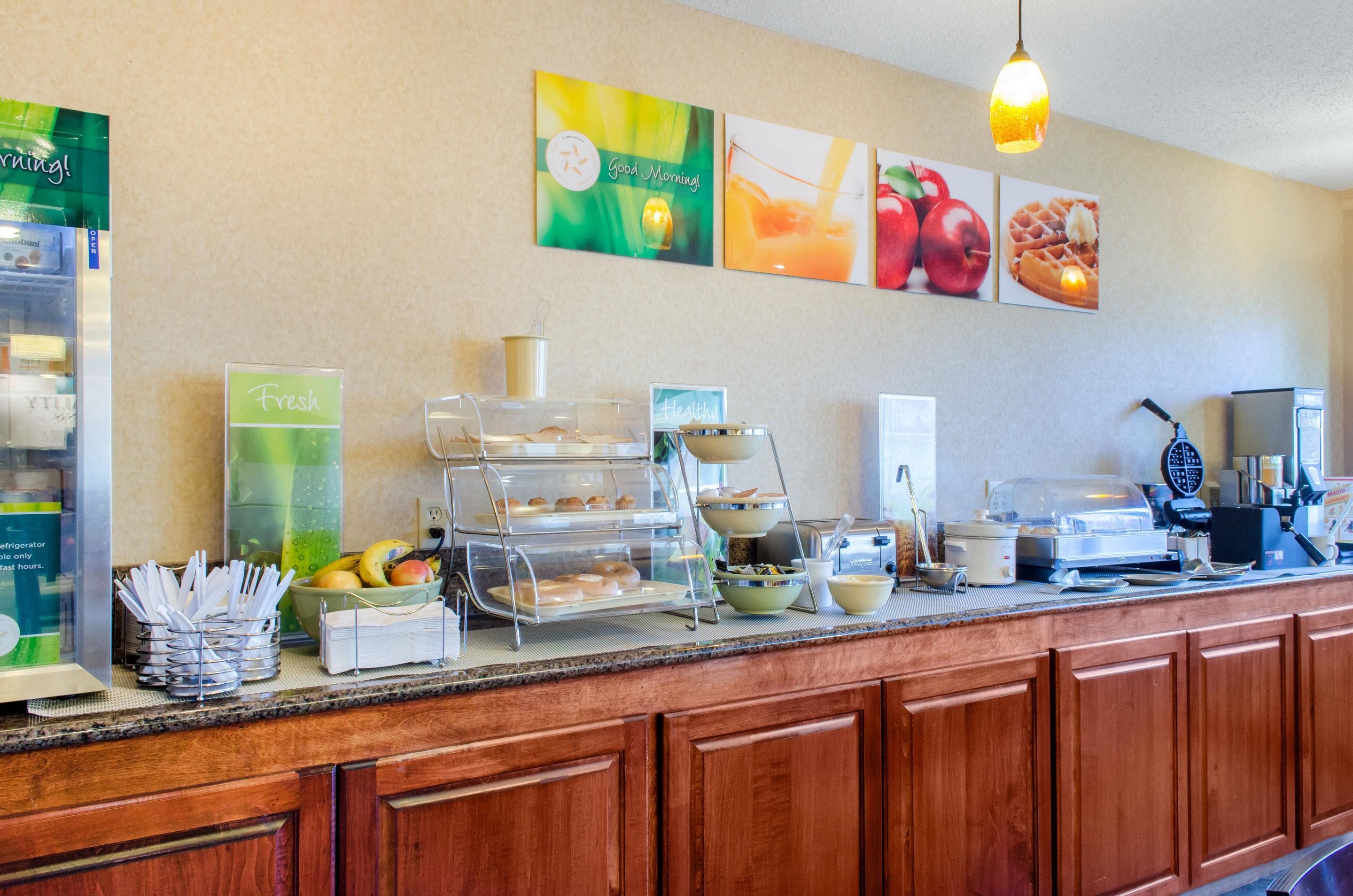 A breakfast bar with a fruit bowl, a fresh sign, and a waffle maker.