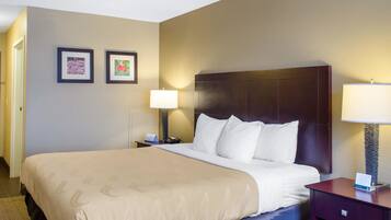 A hotel room with a large bed, two bedside lamps, and two framed pictures on the wall.