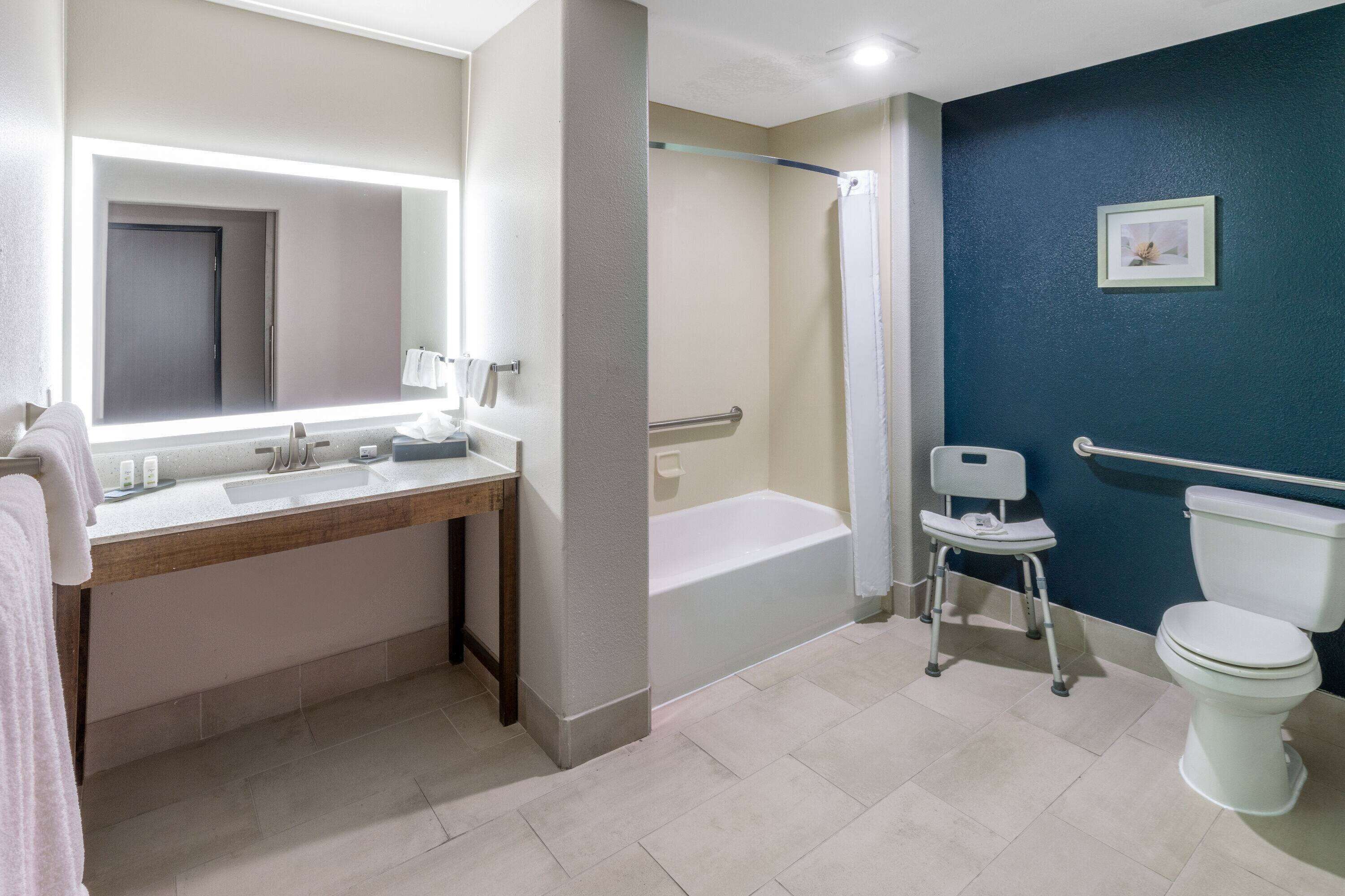 Une salle de bain équipée d’un lavabo, d’un miroir, d’une baignoire et de toilettes.