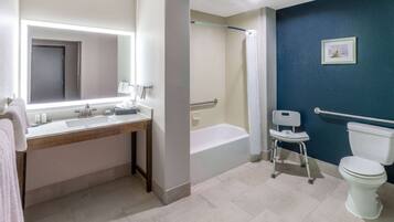 Une salle de bain équipée d’un lavabo, d’un miroir, d’une baignoire et de toilettes.