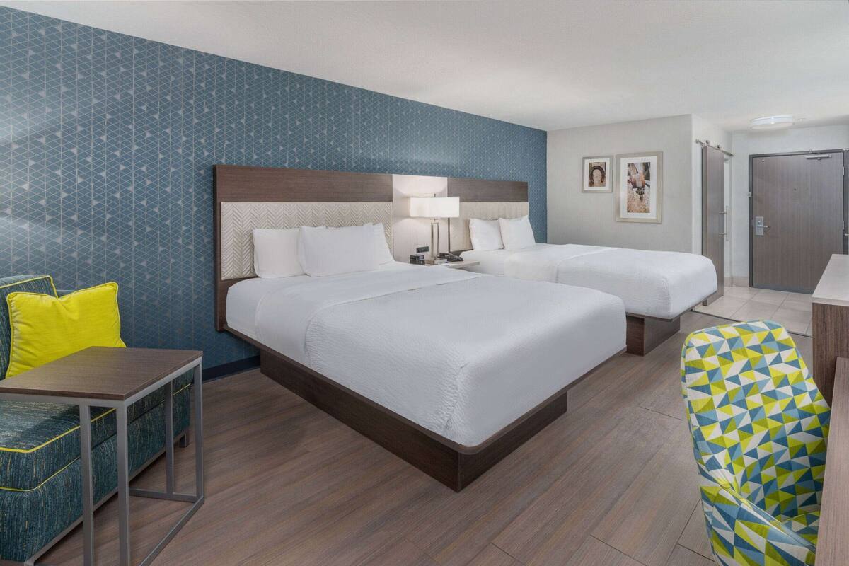 Een hotelkamer met twee bedden, een bureau, een stoel en een kledingkast.