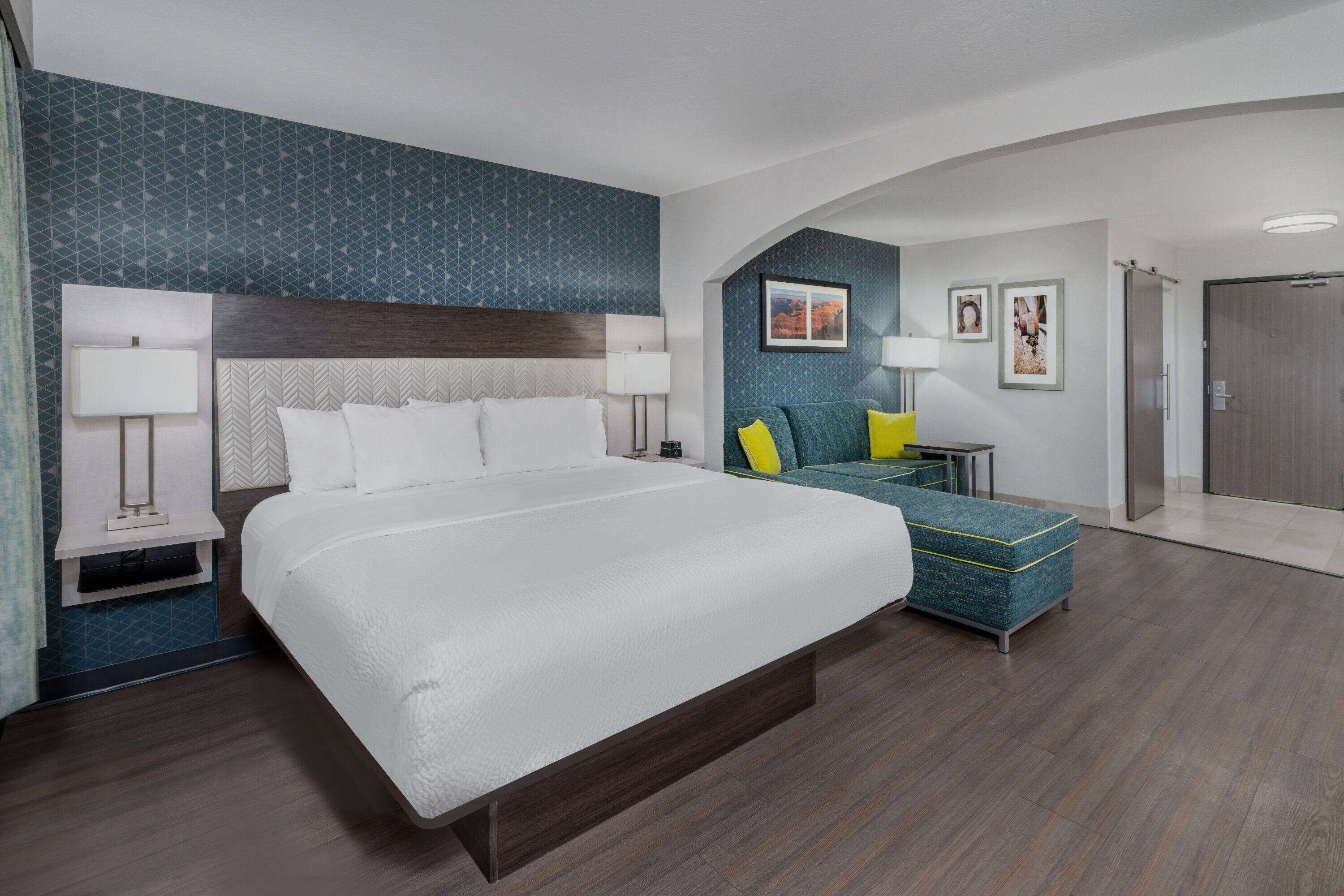 Una habitación de hotel moderna con una cama grande, un sofá y un escritorio con una lámpara.