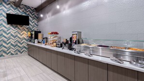 A buffet area with a variety of food options, a beverage dispenser, and a television mounted on the wall. - La Quinta Inn & Suites by Wyndham Santa Rosa (Santa Rosa)