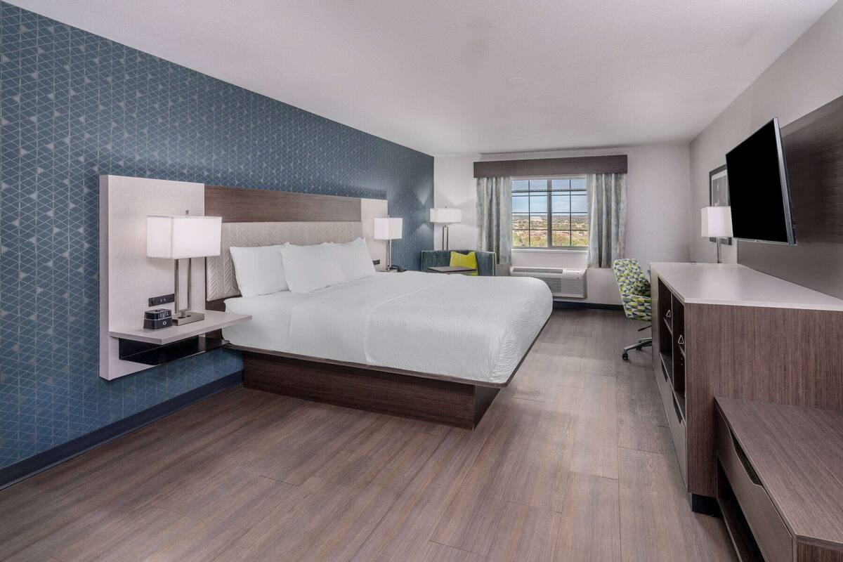 Een moderne hotelkamer met een groot bed, een bureau, een televisie en een raam met uitzicht.