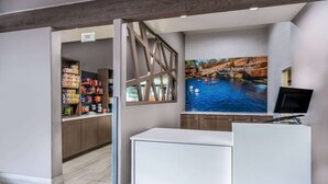 A reception area with a counter, a snack bar, and a large mural of a river scene. - La Quinta Inn & Suites by Wyndham Santa Rosa (Santa Rosa)