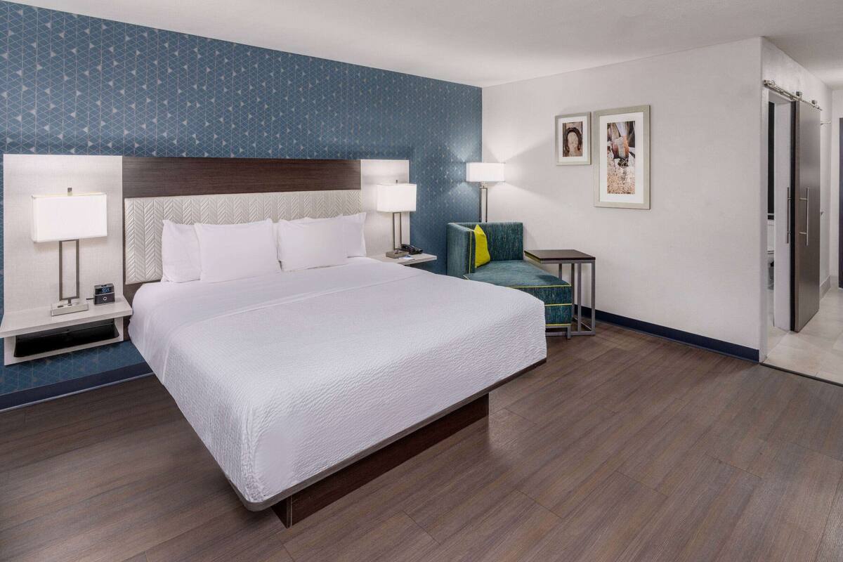 Een hotelkamer met een groot bed, twee nachtkastjes met lampen, een bureau en een stoel.