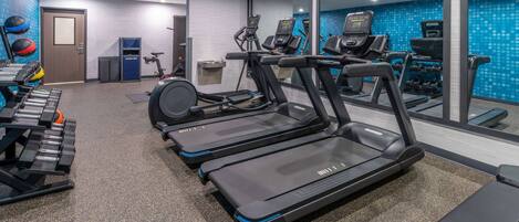 A gym with treadmills, dumbbells, and exercise balls.