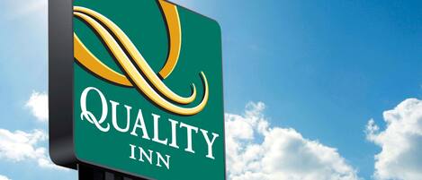 A sign for Quality Inn with a stylized logo and the name of the hotel.