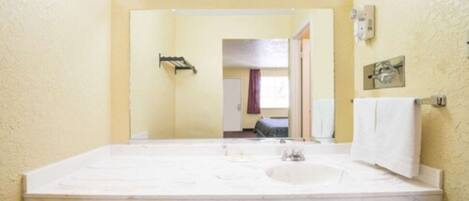 A bathroom with a large marble sink, a mirror, and a towel rack.