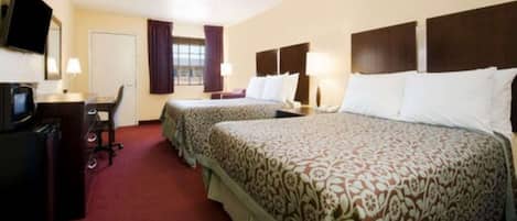 A hotel room with two beds, a desk, a television, and a window with curtains.