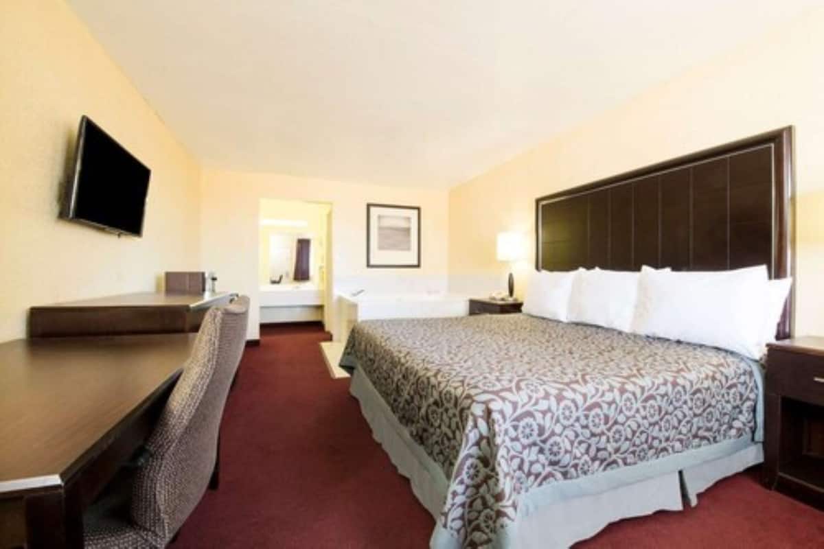Una habitación de hotel con una cama, un escritorio, una silla, un televisor y una mesita de noche.