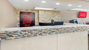 Ein Empfangsbereich mit einem Schild für 'Red Roof Inn' und einem Schild mit der Aufschrift 'Kostenloses WLAN in allen Zimmern'.
