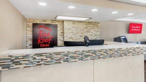 A hotel reception desk with a sign for 'Red Roof Inn' and a 'Free Wi-Fi All Rooms' sign. - Red Roof Inn Kissimmee (Kissimmee)