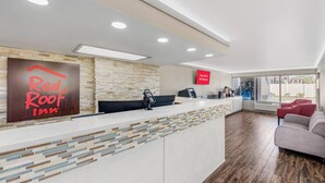 A Red Roof Inn reception area with a modern design, including a reception desk, a stone wall, and a sign indicating free Wi-Fi in all rooms. - Red Roof Inn Kissimmee (Kissimmee)