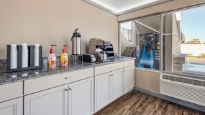 A modern kitchen with a granite countertop, white cabinetry, and a view of a pool through a glass door. - Red Roof Inn Kissimmee (Kissimmee)