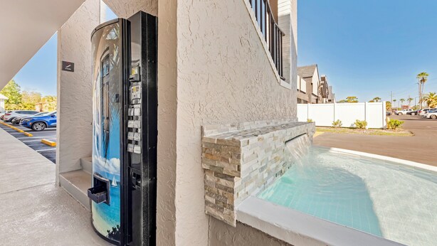 A pool area with a stone wall and a door leading to a covered space. - Red Roof Inn Kissimmee (Kissimmee)