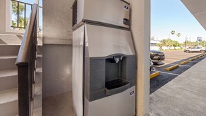 Un dispensador de agua con estación de lavado de manos, situado cerca de una escalera y un aparcamiento.