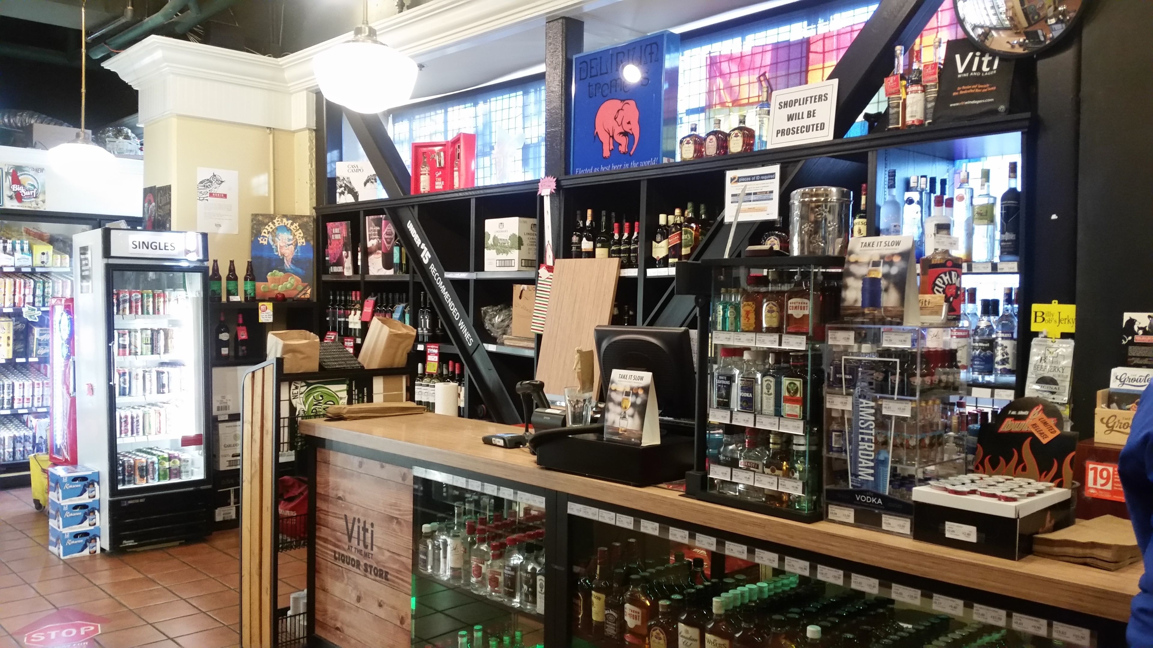 A liquor store with shelves stocked with various bottles and a refrigerated display case.