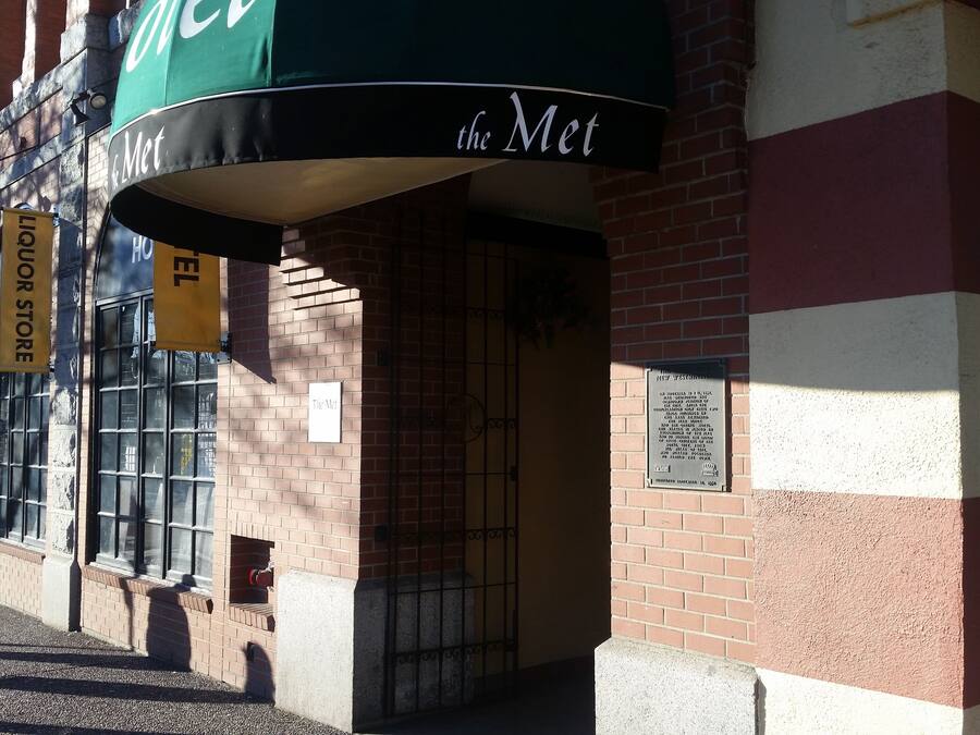 A brick building with a green awning labeled "the Met" and a yellow sign for a liquor store.