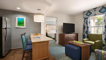 Habitación de hotel pequeña con kitchenette, zona de comedor, televisor y rincón de estar con vistas al exterior.