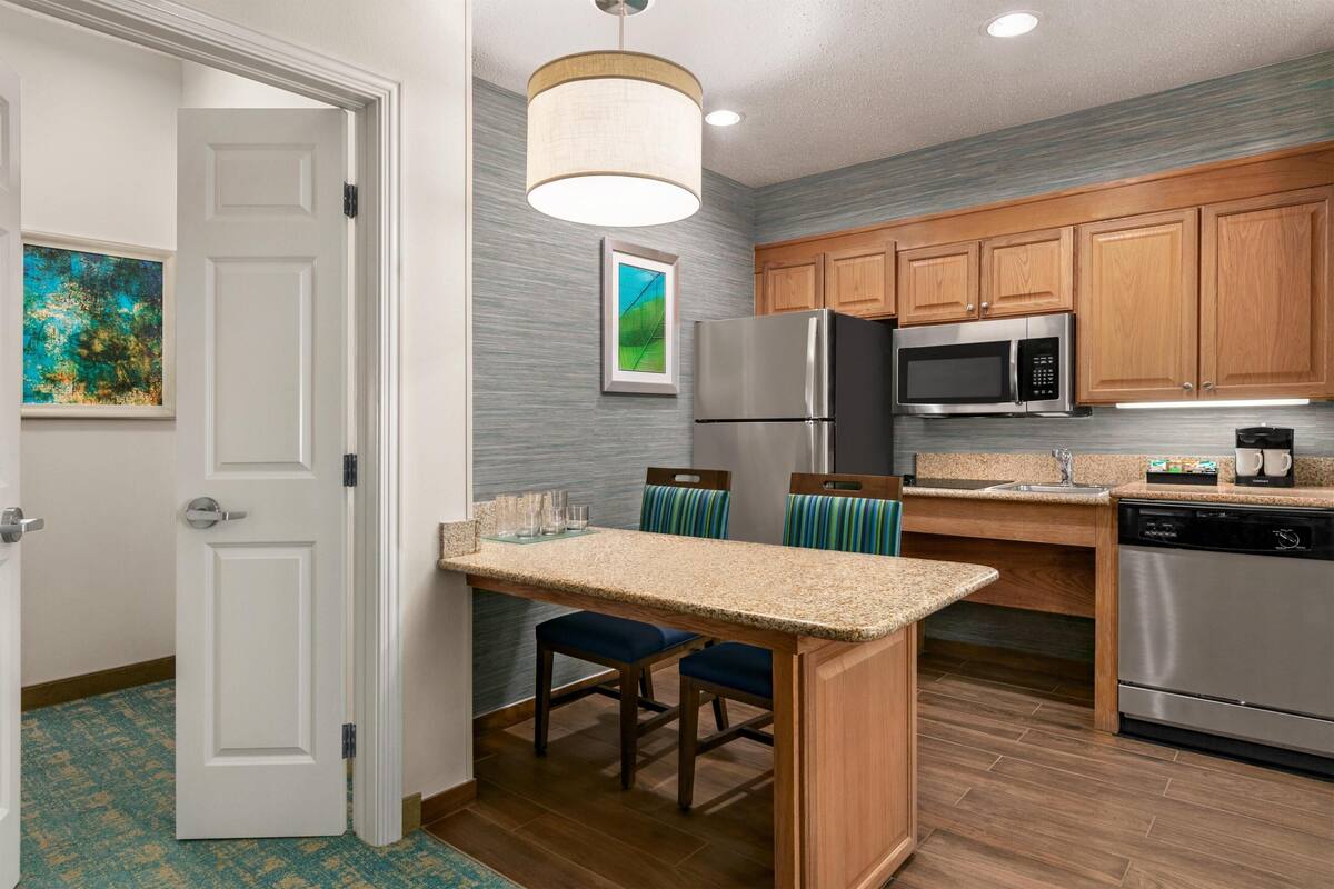 A modern kitchen with wooden cabinets, a stainless steel refrigerator, a microwave, and a dishwasher.