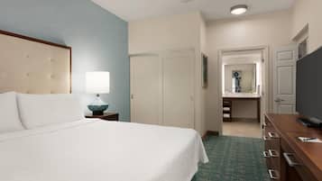 Una habitación de hotel con cama, escritorio, espejo y televisor.