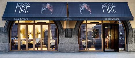 Un ristorante chiamato "Wood Fire" con un tendone nero e vetrate, con il logo raffigurante un cavallo e un cavaliere.