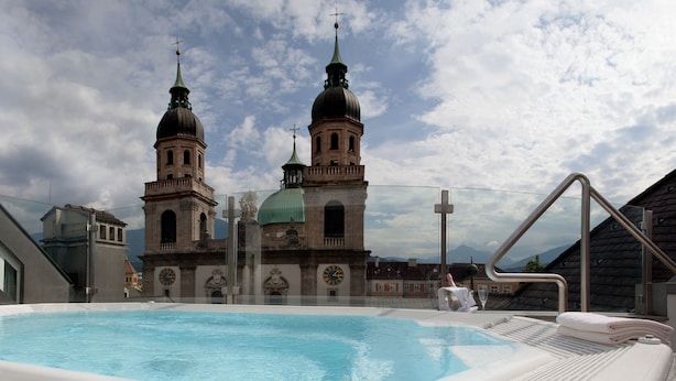 Ein Dachpool mit Blick auf ein historisches Gebäude mit zwei Kuppeln und einer Turmuhr.