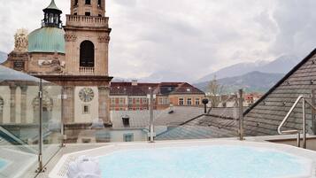 Una piscina en la azotea con vistas a un edificio histórico y montañas al fondo.